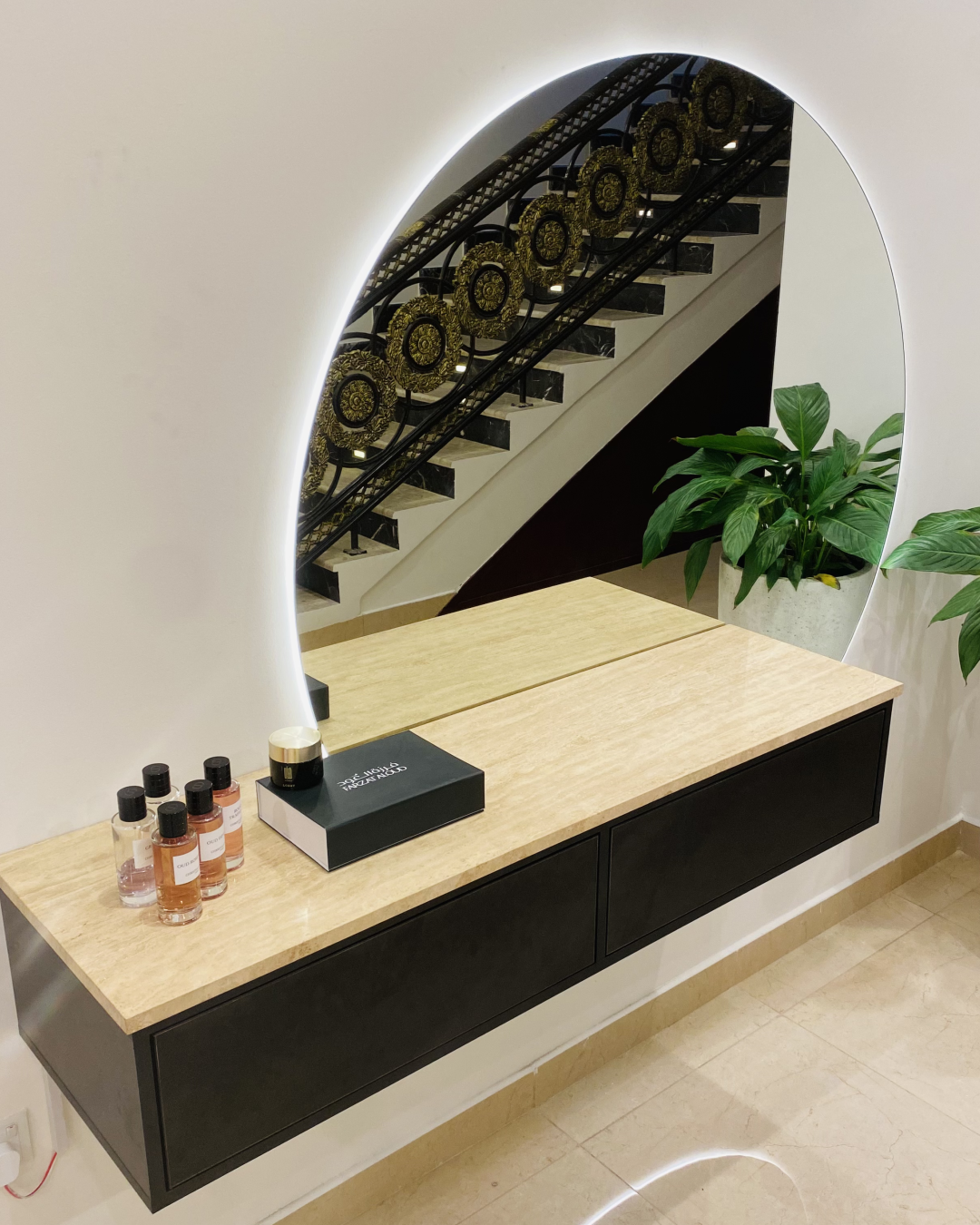 Left-side view of Prismo Vanity Console highlighting travertine top, floating matte black drawers, and LED-backlit circular mirror