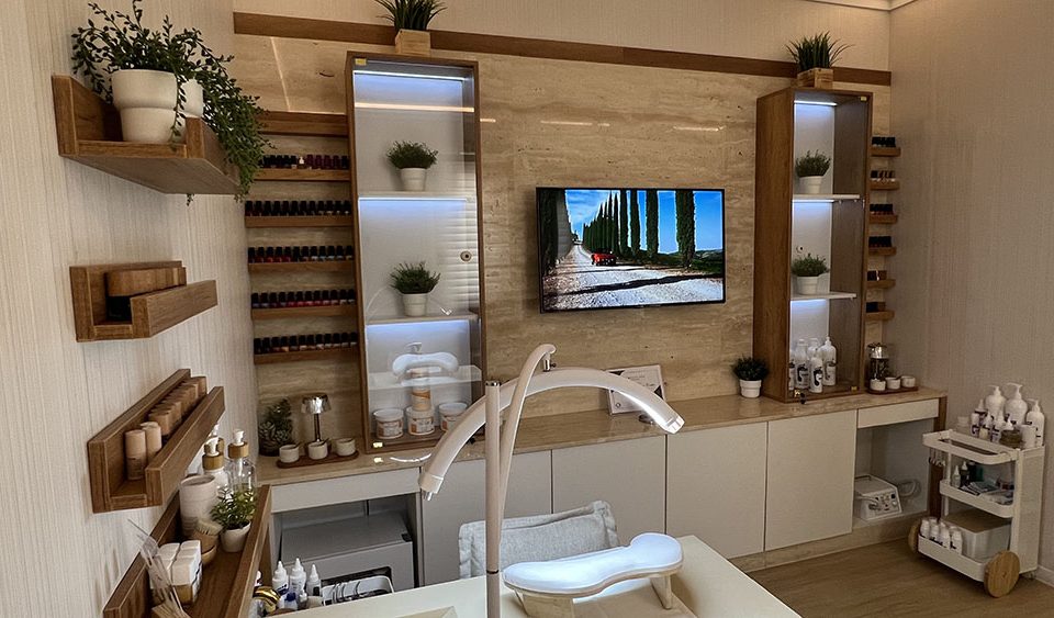 Binan Skin Care Center nail room with travertine TV wall, backlit display shelves, product storage, and custom cabinetry