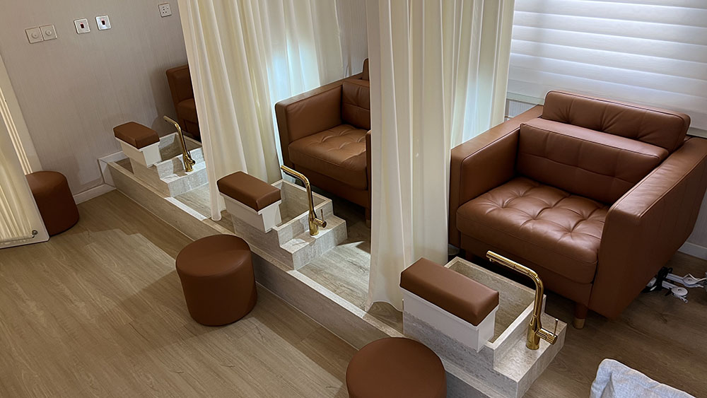 Binan Skin Care Center nail room showing treatment seating, solid surface foot stations, curtains, and warm interior finishes