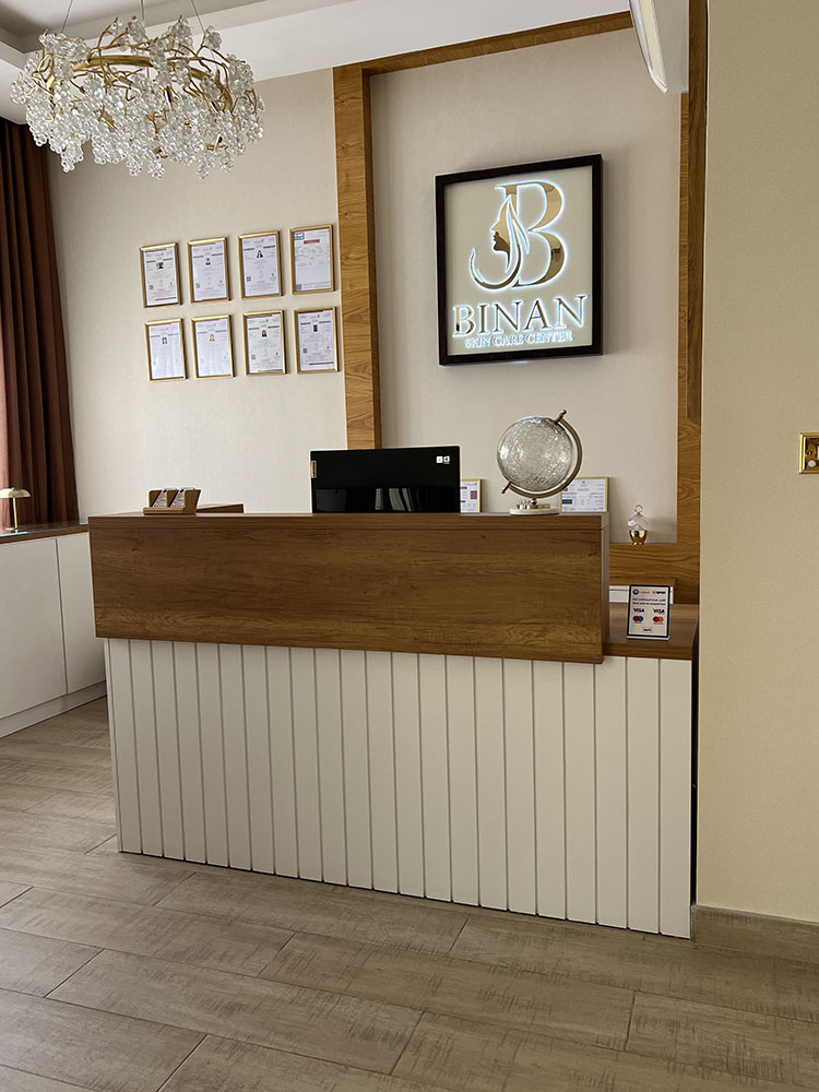 Binan Skin Care Center reception counter with wood-finish top, white fluted front, illuminated logo, and certificate wall