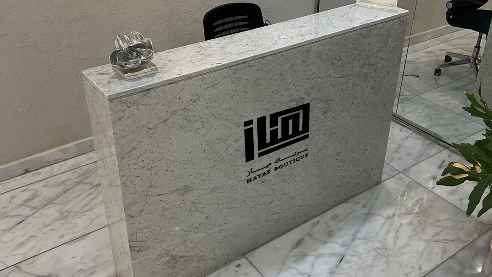 HAYAS Boutique Carrara marble reception counter with logo on the front panel