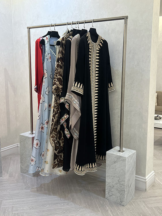 Garments displayed on custom stainless steel rail with Carrara marble base blocks at HAYAS Boutique