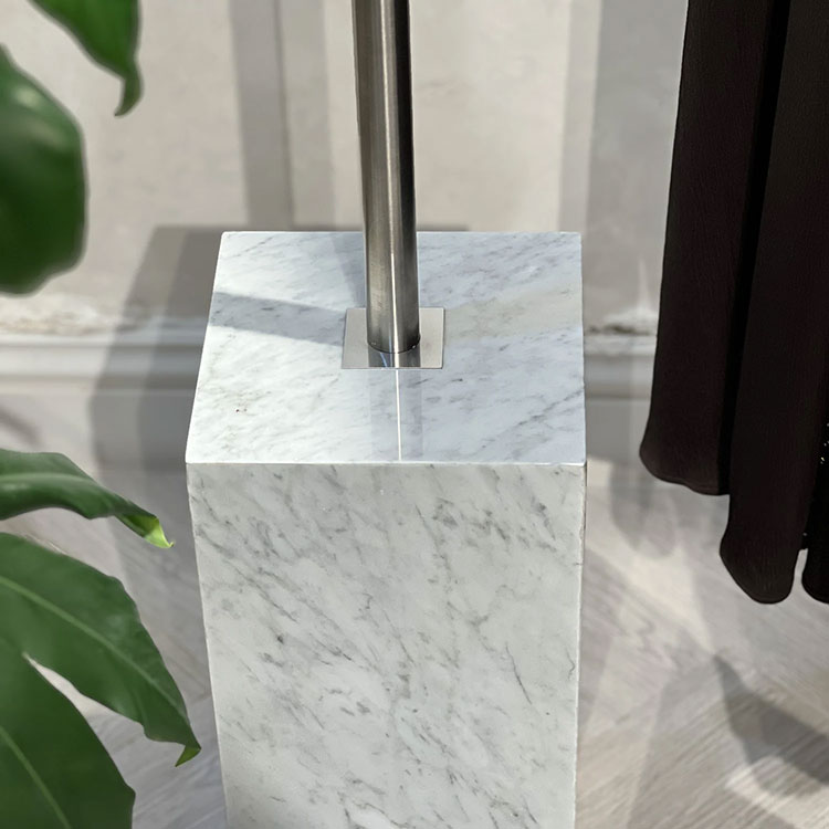 Close view of Carrara marble base detail supporting a garment rail at HAYAS Boutique