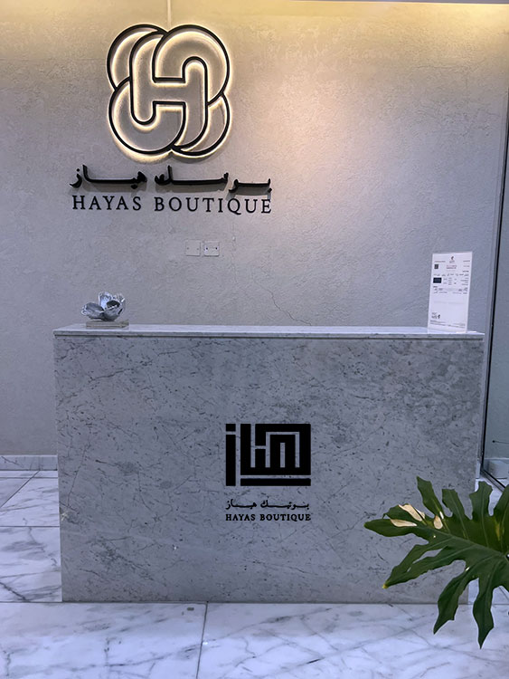 HAYAS Boutique Carrara marble reception counter with illuminated logo wall