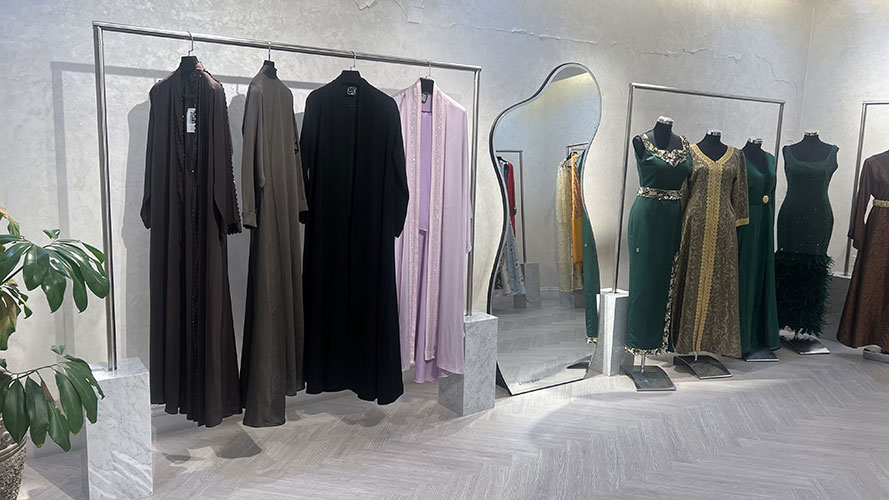 Stainless steel garment rails with Carrara marble bases displaying abayas and dresses at HAYAS Boutique