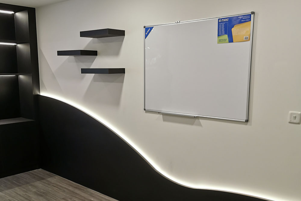 With Vibes training wall with floating shelves, whiteboard, black wall cladding, and concealed LED lighting